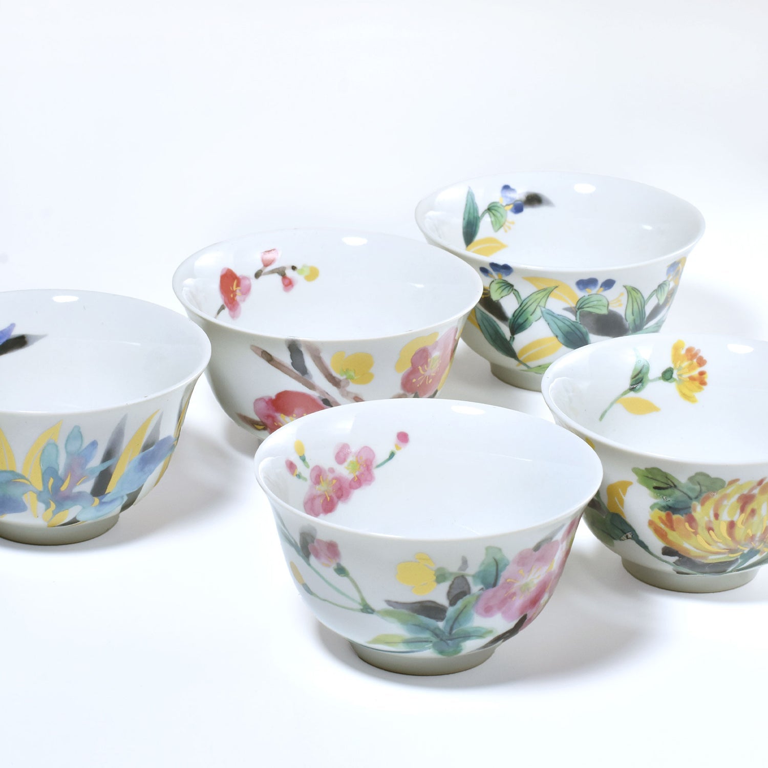 Set of ceramic cups with floral designs on a white background