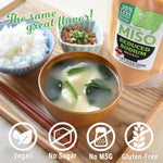 Bowl of miso soup with ingredients and a bottle of reduced sodium miso on a wooden board.