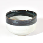 Ceramic matcha bowl with dark rim on a white background