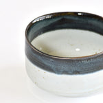 Ceramic matcha bowl with dark rim on a white background