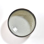 Ceramic matcha bowl with dark rim on a white background