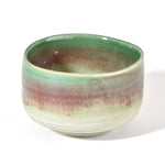 Ceramic matcha bowl with green and brown gradient on a white background