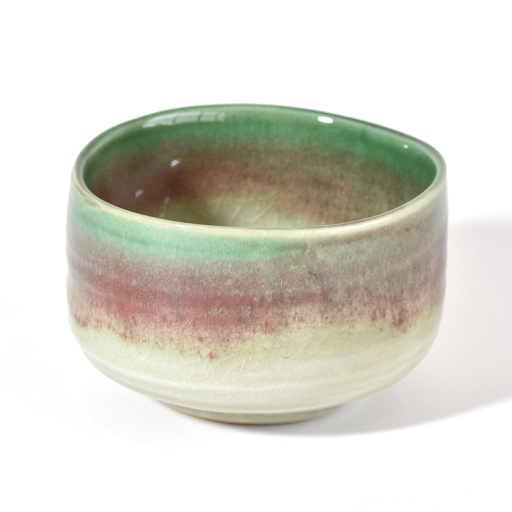 Ceramic matcha bowl with green and brown gradient on a white background