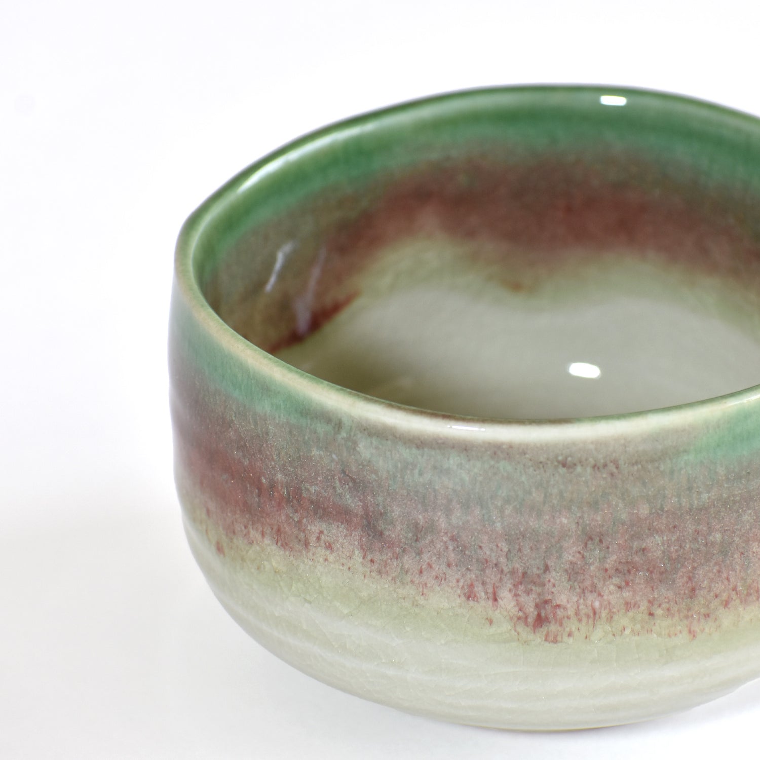 Ceramic matcha bowl with green and brown gradient on a white background