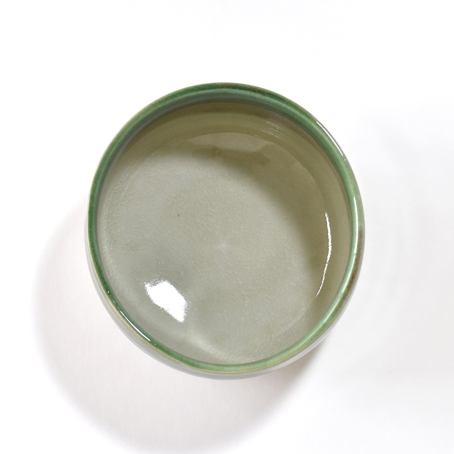 Ceramic matcha bowl with green and brown gradient on a white background