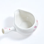 White ceramic teapot with floral patterns on a white background