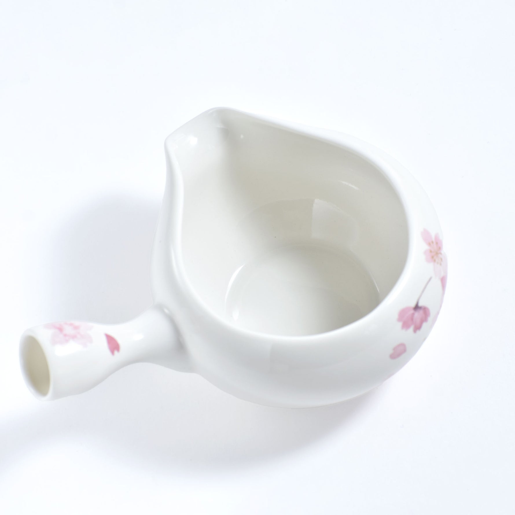 White ceramic teapot with floral patterns on a white background