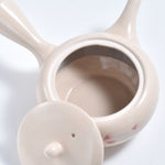 White ceramic tea infuser with a mesh filter on a white background