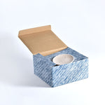 Ceramic candle holder in a blue marbled box with a cardboard lid on a white background