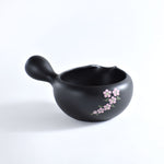 Black ceramic spoon rest with floral design on a white background