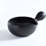 Black ceramic tea cup with handle on a white background