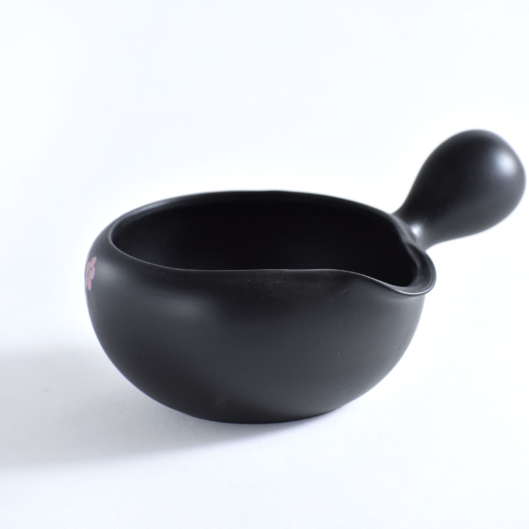 Black ceramic tea cup with handle on a white background