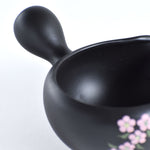 Black ceramic bowl with floral design on a white background