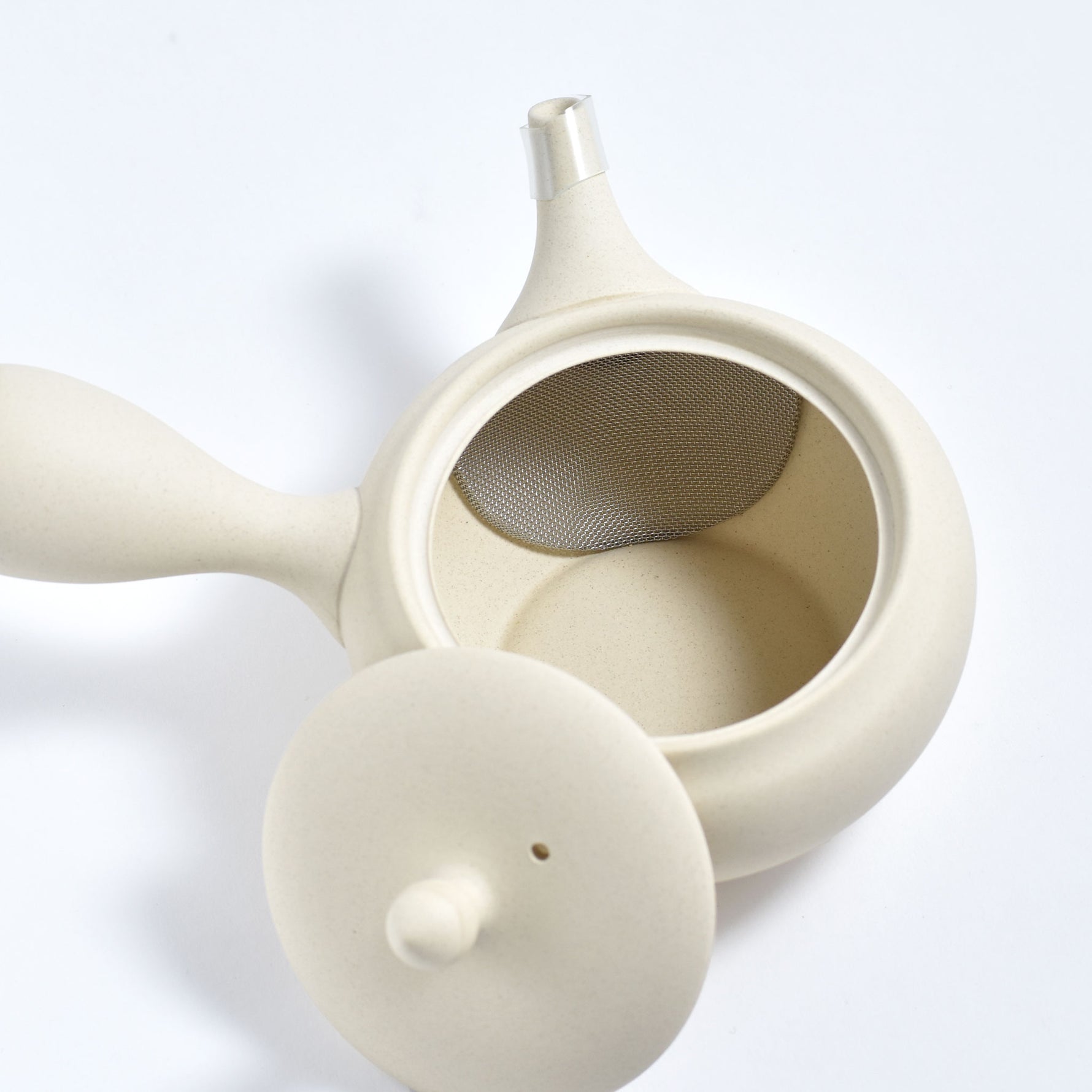 White ceramic teapot with a mesh filter on a white background