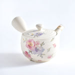 Ceramic teapot with floral design on a white background
