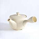 Cream-colored ceramic teapot on a white background
