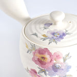 Ceramic teapot with floral designs on a white background