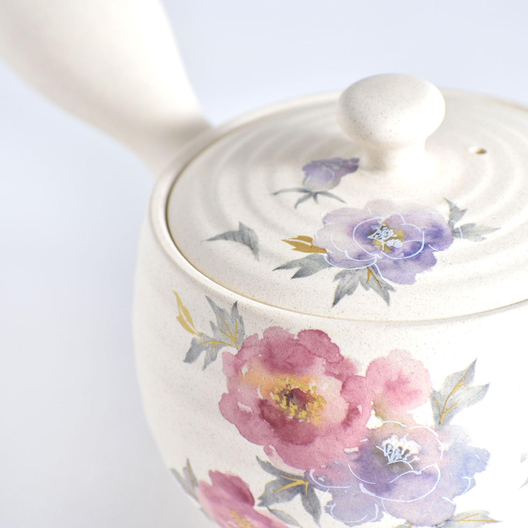 Ceramic teapot with floral designs on a white background