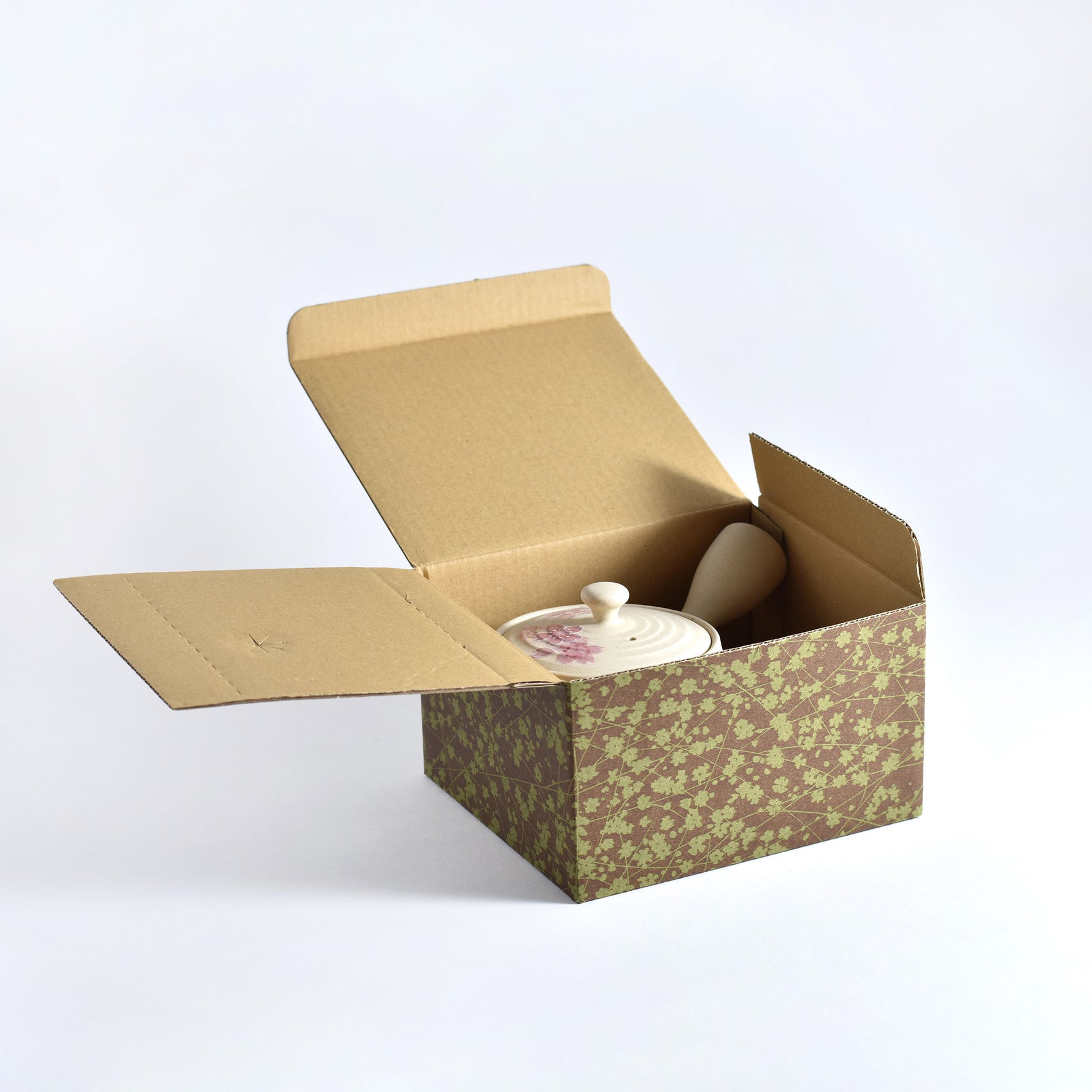Open cardboard box with a ceramic container inside on a white background