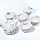 Set of ceramic teacups and teapot with floral patterns on a white background