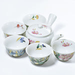 Ceramic teapot and cups with floral designs on a white background