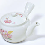 White ceramic teapot with floral designs on a white background