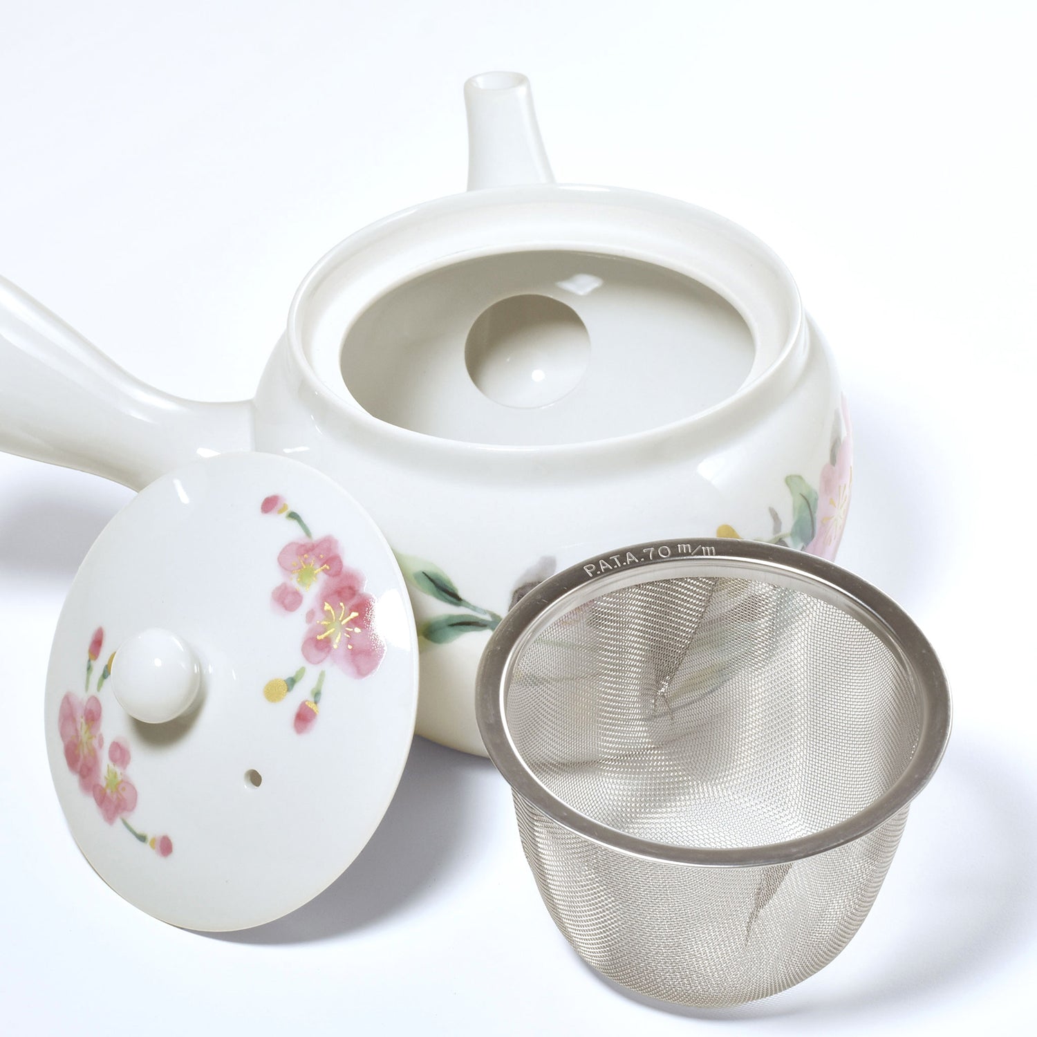 White ceramic teapot with floral design and metal mesh filter on a white background
