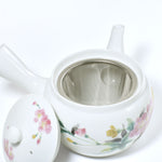 White ceramic teapot with floral designs on a white background