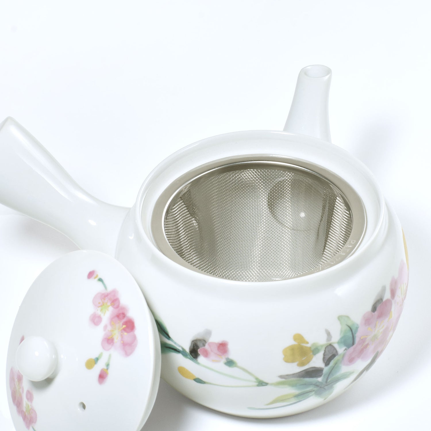 White ceramic teapot with floral designs on a white background