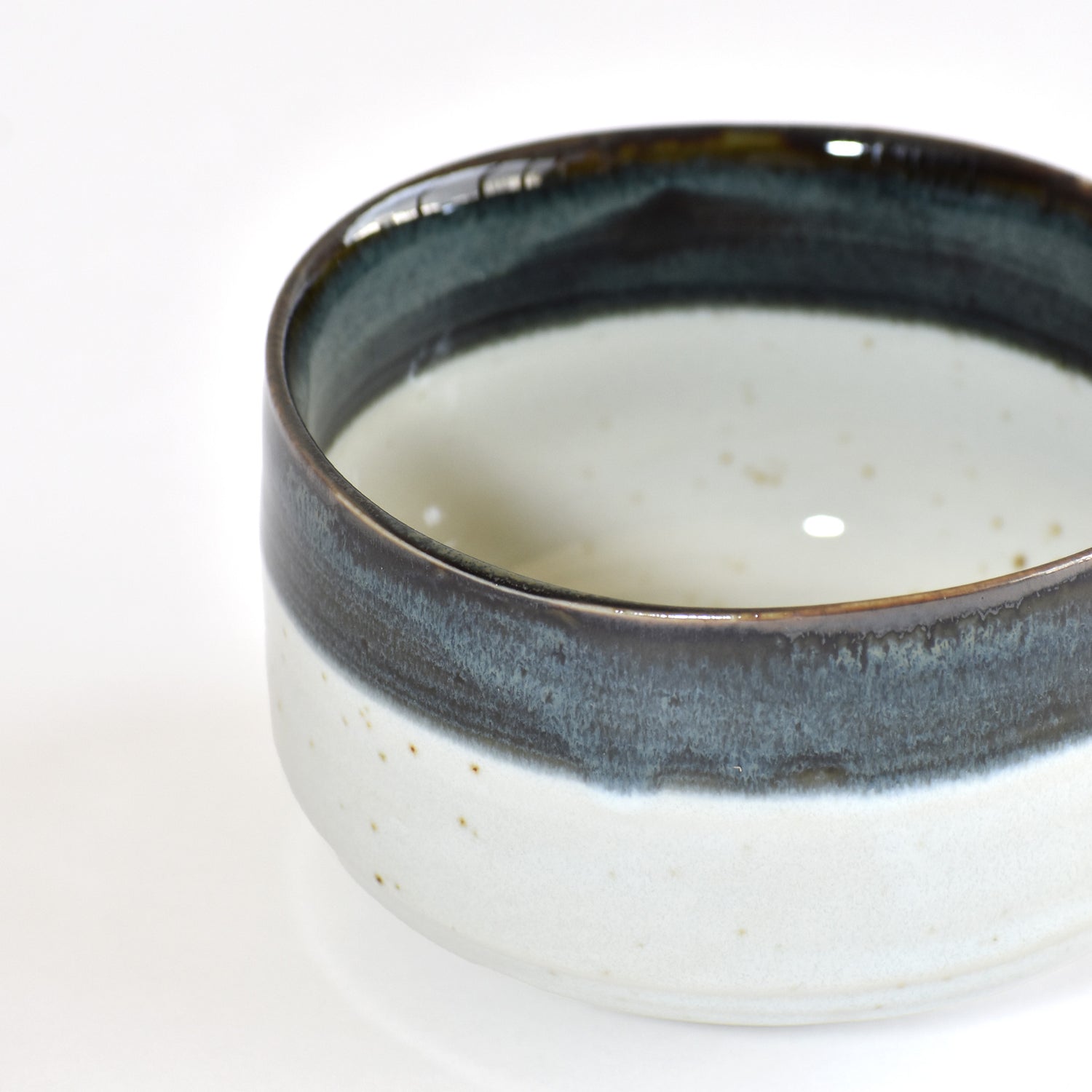 Ceramic matcha bowl with dark rim on a white background