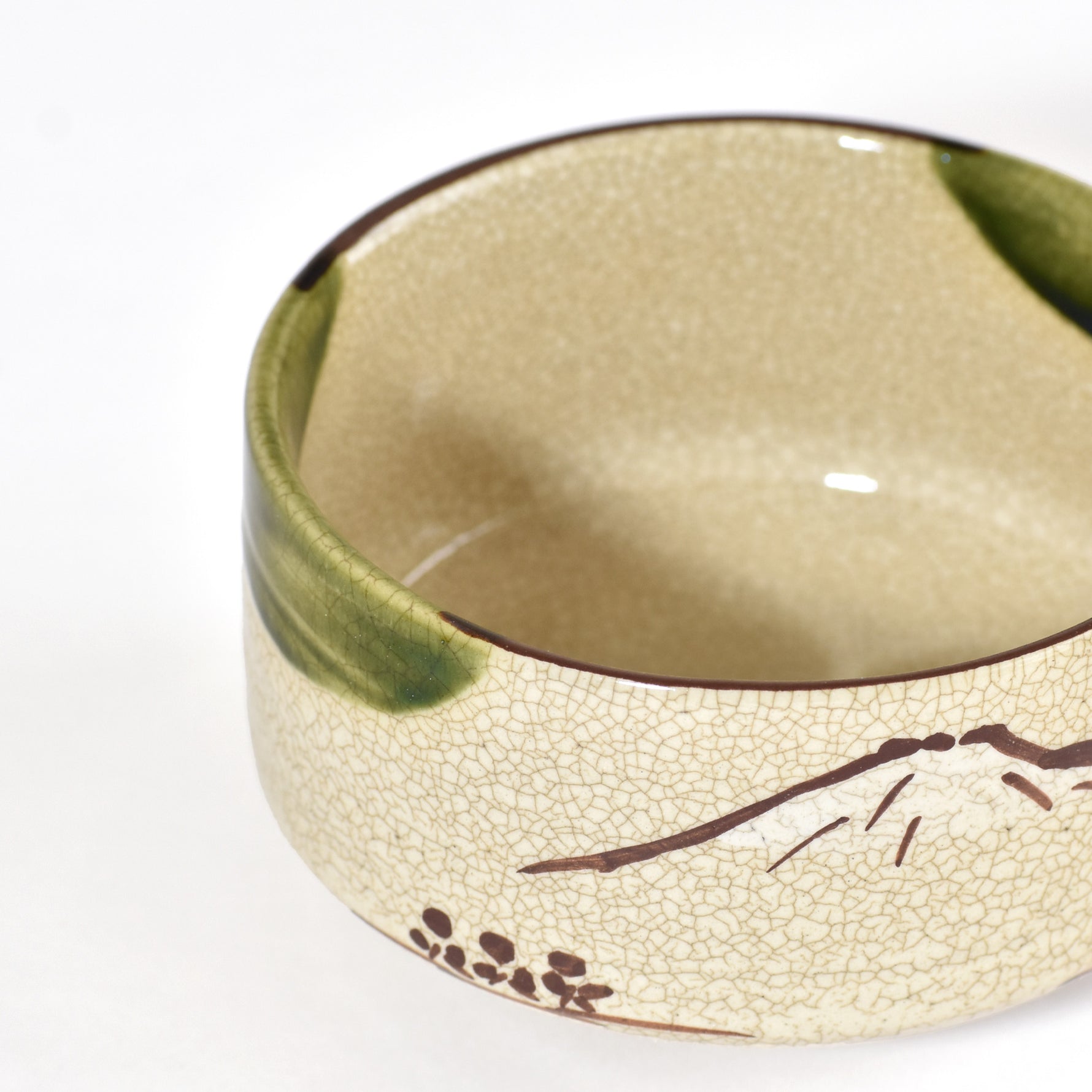 Ceramic bowl with green interior and decorative elements on a white background