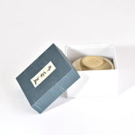 Blue box with a lid open, revealing a woven item inside on a white background