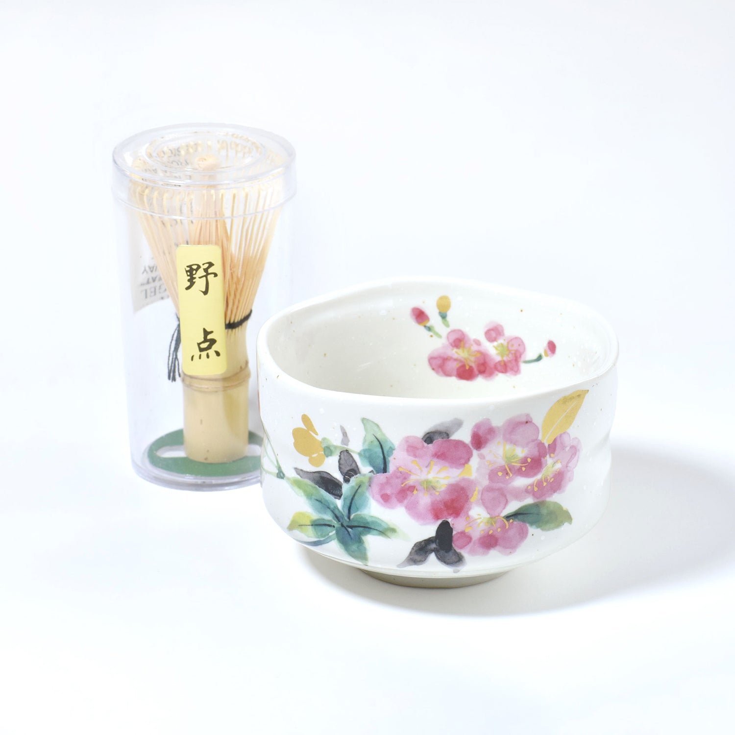 Matcha bowl with floral design and bamboo whisk on a white background