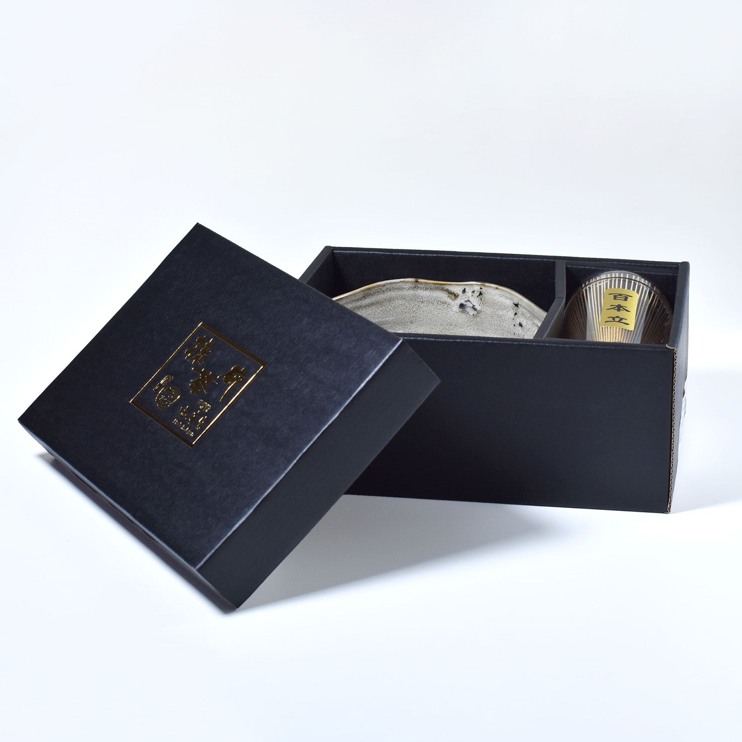 Gray ceramic matcha bowl and bamboo whisk set in a box on a white background