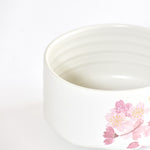 White ceramic bowl with pink floral design on a white background