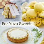 Yuzu sweets including a tart, macarons, and a gift with a tag on a light background.