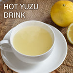 Hot yuzu drink in a white cup with yuzu fruit on a woven mat